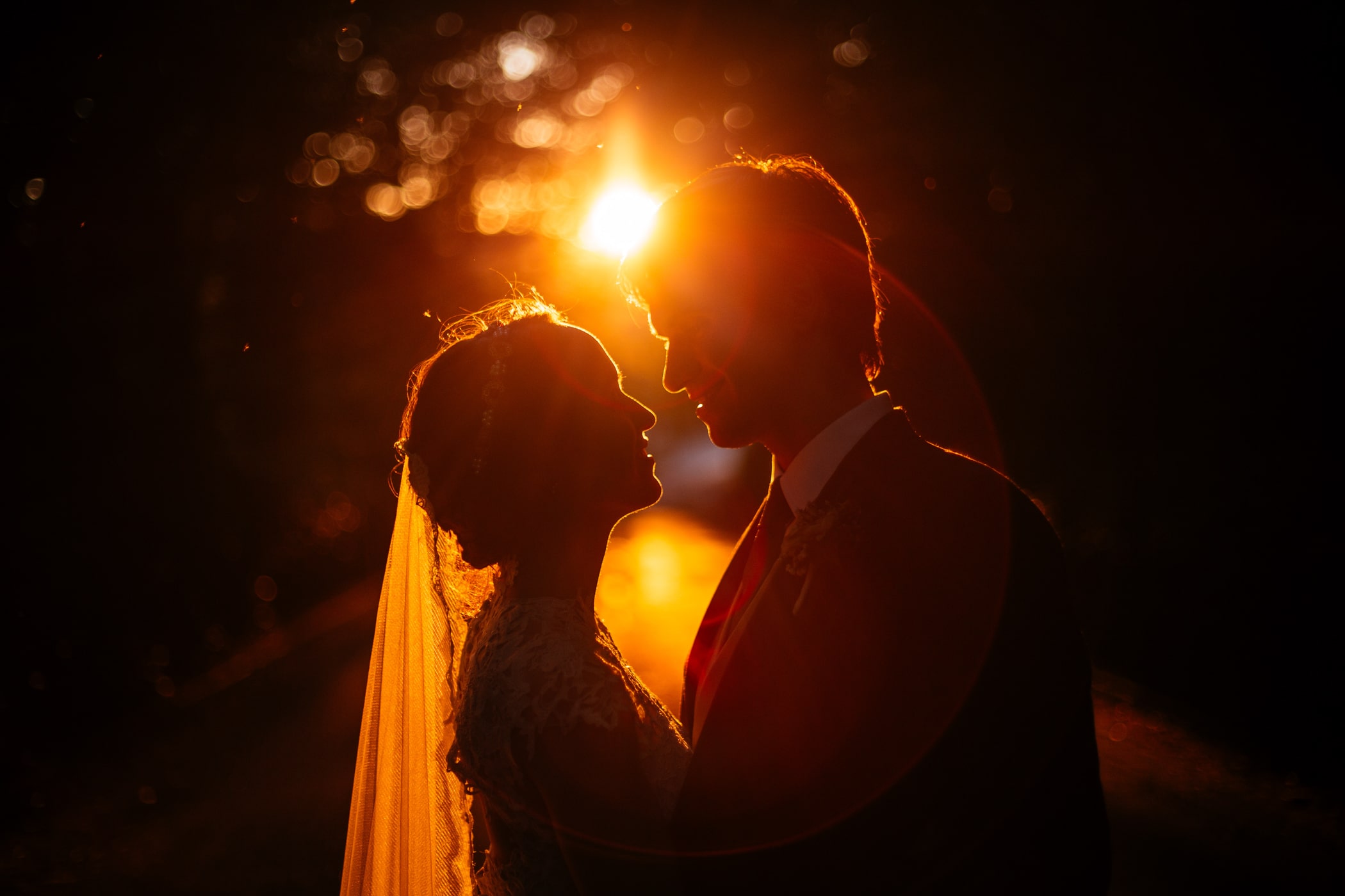 A bride and groom silhouetted against the setting sun