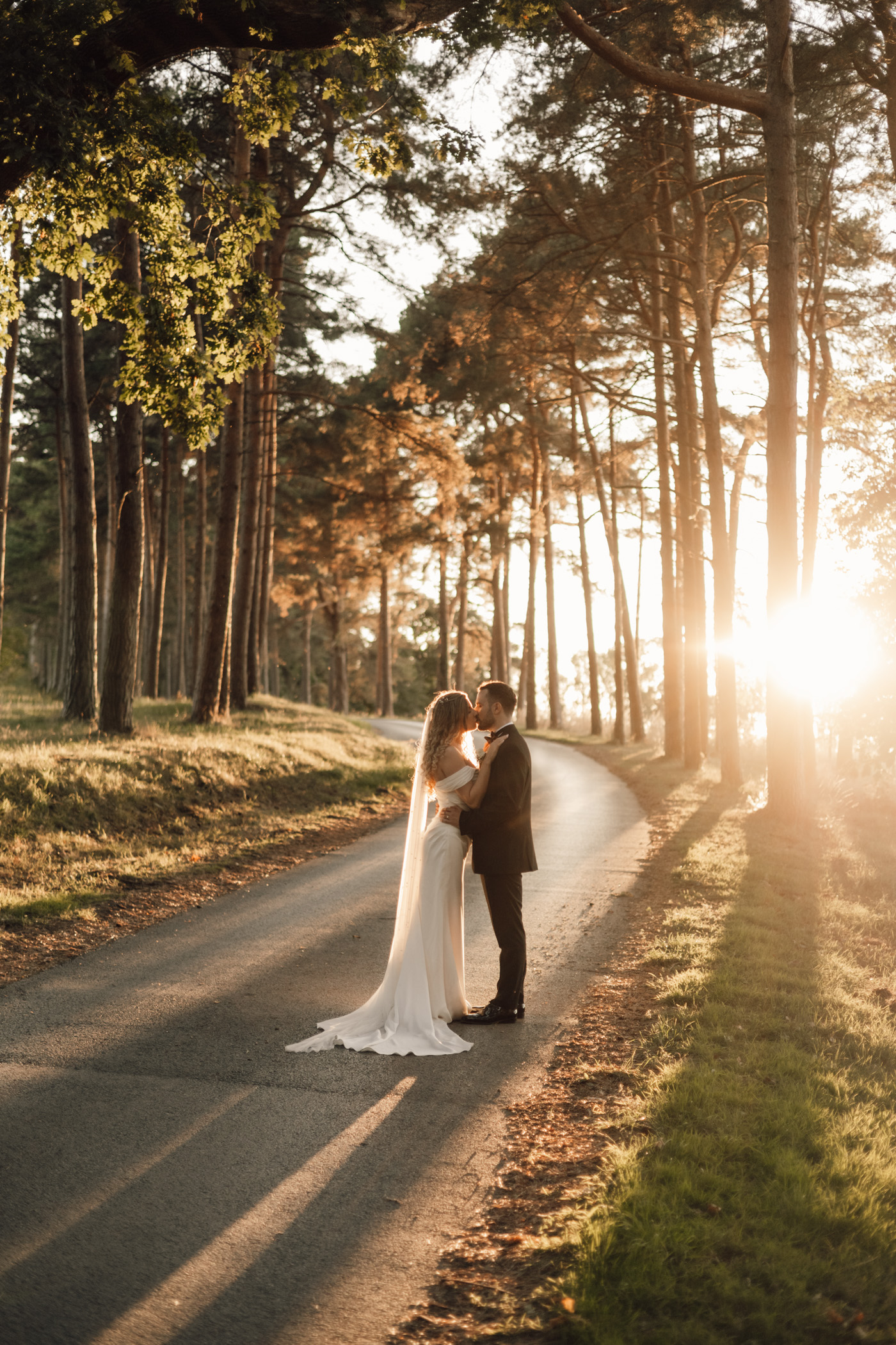 Ruby and Luke kissing on a tree-lined lane at sunset, Harewood